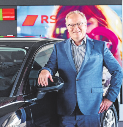 Stefan Carstens im Autohaus neben einem Fahrzeug